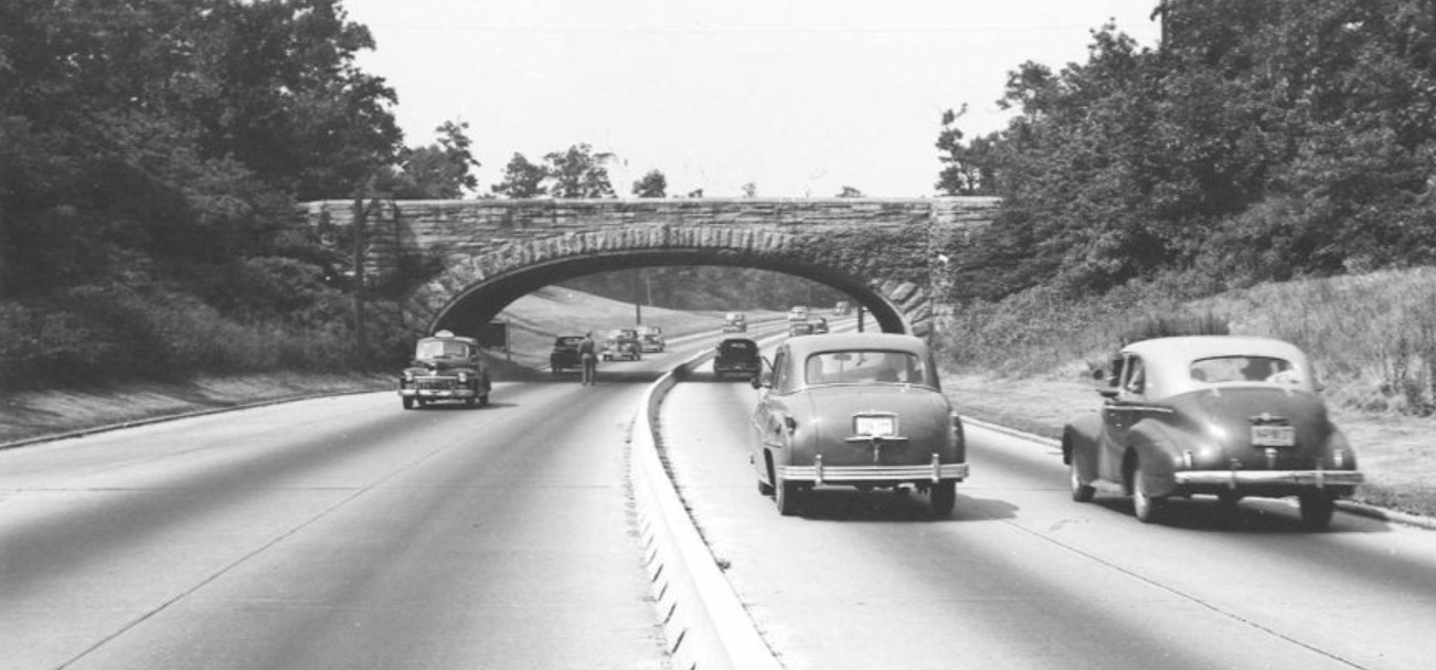 Picture in black of white of cars driving under a bridge